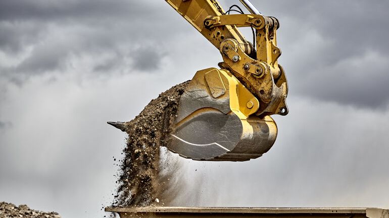Gravemaskin med skuffe fylt med jord